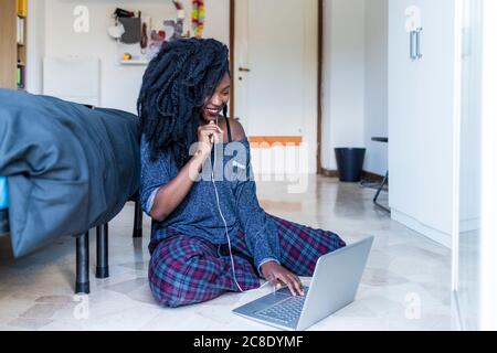 Young woman using laptop and earphones at home Stock Photo