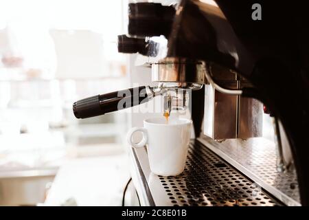 Coffee being poured in cup from machine in bakery Stock Photo