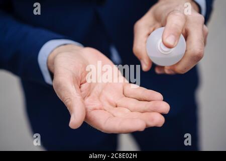 Close-up of businessman disinfecting his hands with a spray Stock Photo