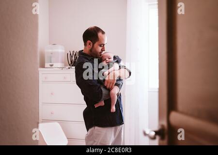 Father carrying cute baby girl in living room at home Stock Photo