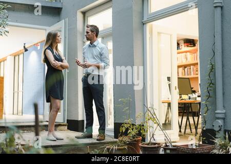 Businessman and woman talking in backyard of loft office Stock Photo