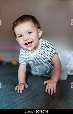 Portrait of happy baby girl crawling on bed Stock Photo