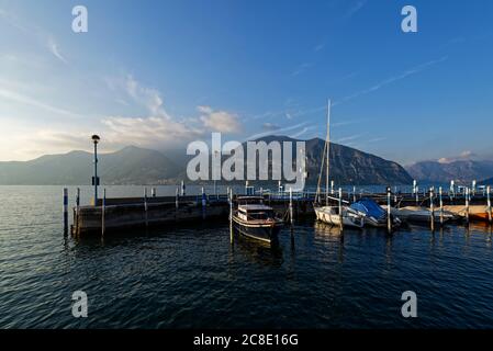 Italy, Lombardy, Boats moored at pier on lake Iseo at sunset Stock Photo