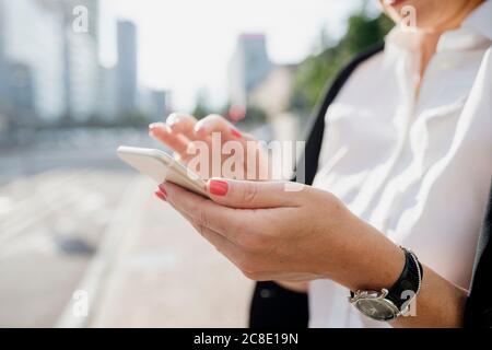Close-up of businesswoman using smart phone in city Stock Photo