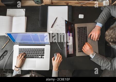 Businessman and woman using laptops at desk in office Stock Photo