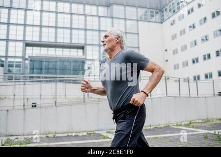 Senior man running against building in city Stock Photo