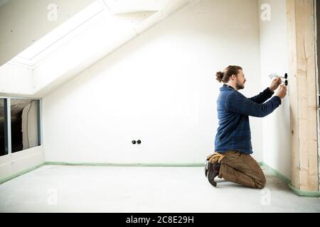 Construction worker installing wires in renovating house Stock Photo