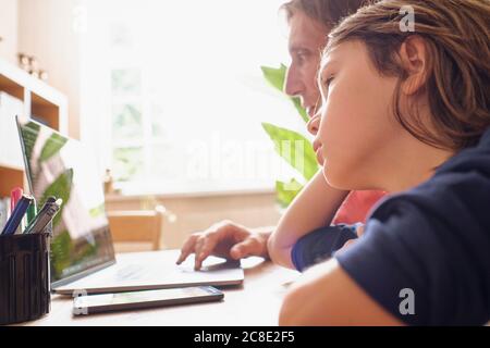 Father and son using laptop while doing studying at home Stock Photo