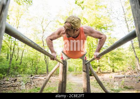 Mature man doing push-ups on parallel bars at park Stock Photo