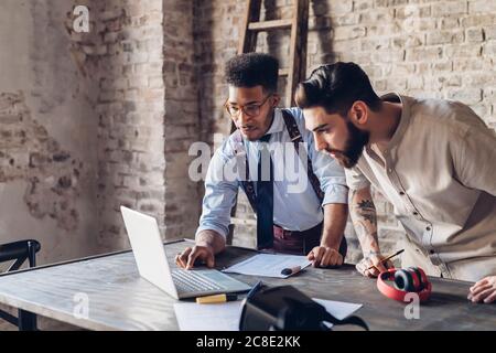 Two creative businessmen using laptop in loft office Stock Photo