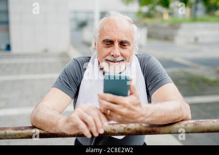 Close-up of senior man using smart phone while standing by railing Stock Photo