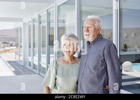 Happy senior couple standing at luxury beach house Stock Photo