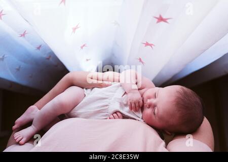Cute baby girl being carried by mother by window Stock Photo