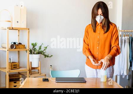 Female fashion designer working at home wearing protective face mask