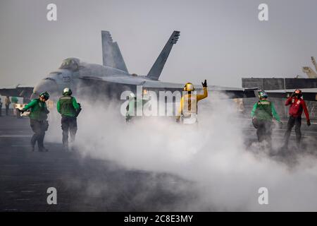 A U.S. Navy deck crew prepare to launch a F/A-18E Super Hornet attached to the Wildcats of Strike Fighter Squadron 131 launches from the flight deck of the Nimitz-class aircraft carrier USS Dwight D. Eisenhower during operations July 18, 2020 in the Arabian Sea. Stock Photo