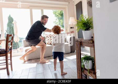 Happy father and son playing in living room at home