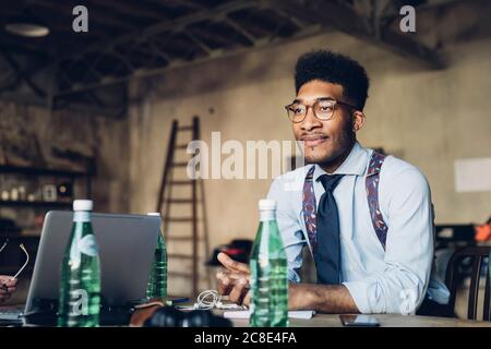 Portrait of stylish young businessman sitting at table in loft office Stock Photo