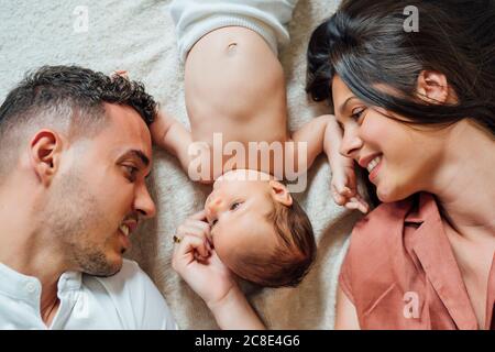 Loving parents lying with baby boy in bedroom at home Stock Photo