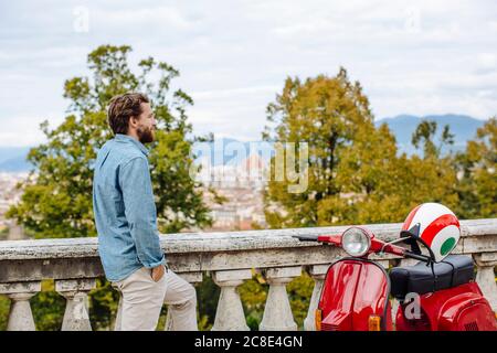 Thoughtful young man standing by railing against sky Stock Photo