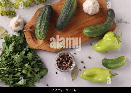 Ingredients for pickling vegetables: cucumbers, peppers, dill, parsley, bay leaf and garlic on a gray background, view from above Stock Photo