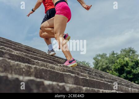 Close up and low below angle view photo of athletes legs running up concrete stairs Stock Photo