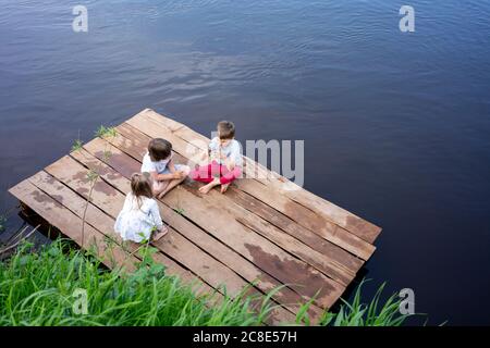 Children playing on pier over lake in forest Stock Photo