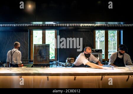 Chefs wearing protective face masks working together in restaurant kitchen Stock Photo