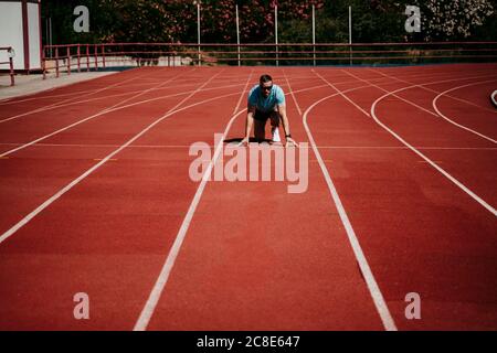 Male athlete in starting position on tartan track Stock Photo