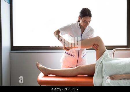 Female physiotherapist treating leg of female patient Stock Photo