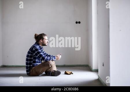 Worker on a construction site sitting on the floor holding tablet Stock Photo