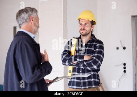 Architect and construction worker discussing while standing in constructing home Stock Photo