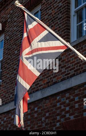 A Union Jack flag or British flag flying on a flag pole on the side of a building Stock Photo