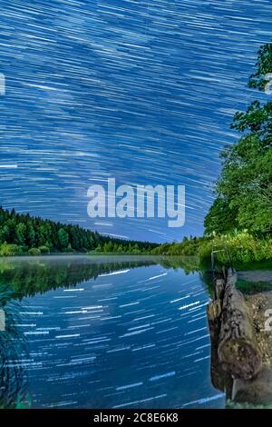 Long Exposure Star-trails over an idyllic lake with star reflections in the water - wonderful star clear night. Stock Photo