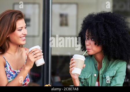 Girlfriends with coffee to go in cafe Stock Photo
