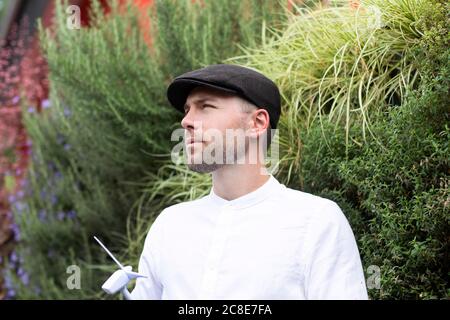 Thoughtful male entrepreneur holding wind turbine model by plants in park Stock Photo