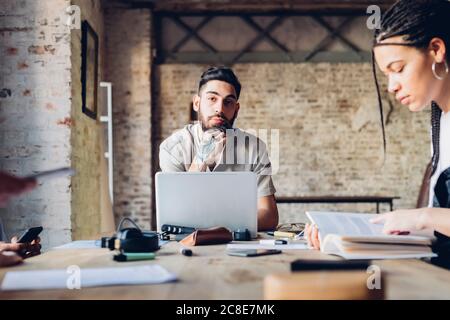 Portrait of creative business man sitting at table in loft office Stock Photo