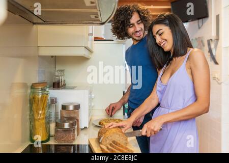Smiling young couple preparing meal in kitchen at home Stock Photo