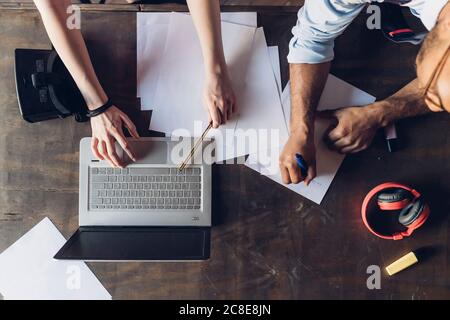 Two creative business people working with laptop and papers on wooden table Stock Photo