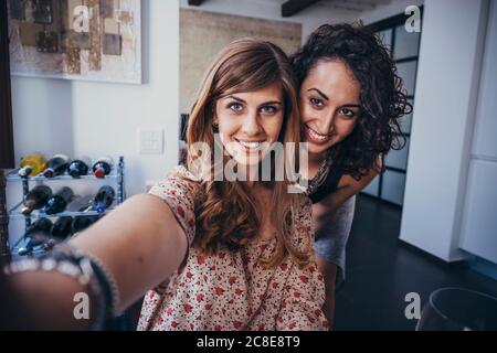 Beautiful young happy multi-ethnic female friends enjoying together at home Stock Photo