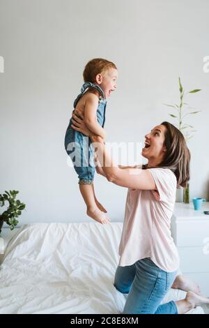 Mother playing with baby girl on bed Stock Photo
