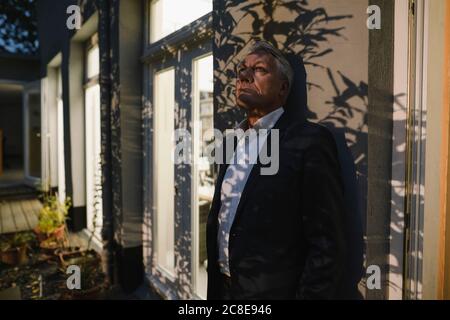 Senior businessman working overtime, taking a break in the backyard of his office Stock Photo