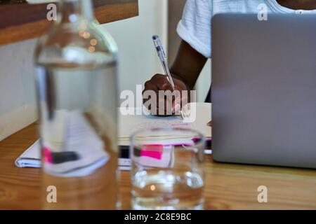 Close-up of young woman writing notes in book on table at home Stock Photo