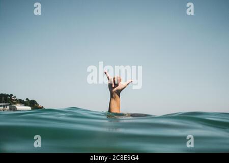 Womans hand making surfer's sign in water Stock Photo