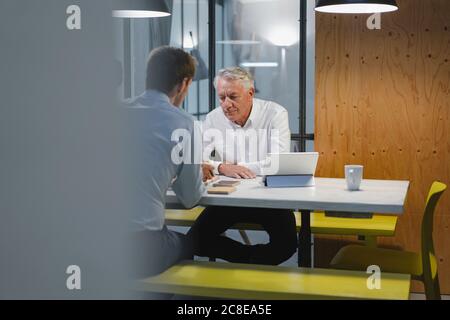 Two businessmen sitting in office, working together Stock Photo