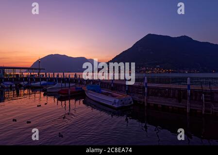 Italy, Lombardy, Sulzano, Boats and pier on lake Iseo at sunset Stock Photo