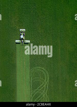 Russia, Moscow Oblast, Aerial view of tractor mowing green field Stock Photo