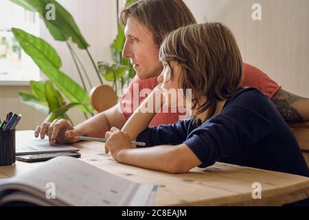 Father and son using laptop while doing homework at home Stock Photo