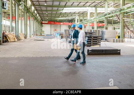 Two businessmen having a meeting and walking in a factory Stock Photo