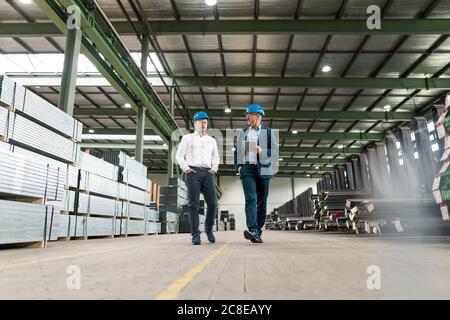Two businessmen having a meeting and walking in a factory Stock Photo