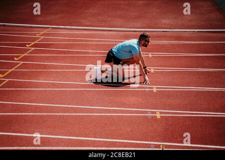 Male athlete in starting position on tartan track Stock Photo